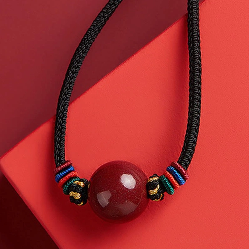 Hanging cinnabar bead Buddhist pendant - large red bead with gold metal accents and colorful braided decorative knots