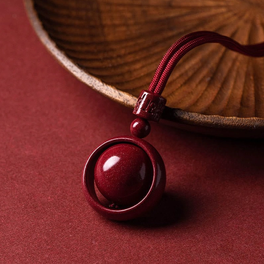 Cinnabar pendant necklace side angle view showing braided red rope and compact pendant structure
