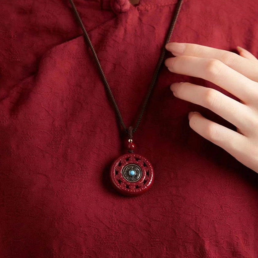 Wearing cinnabar Buddhist pendant necklace on fabric showing slim woven lanyard styling