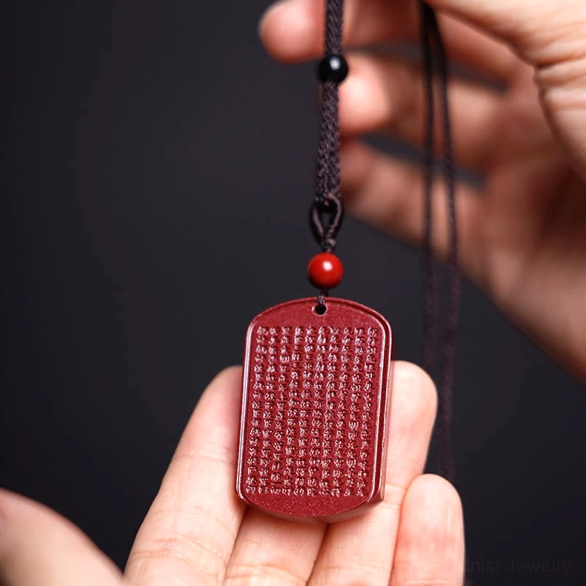 Heart sutra pendant in palm showing full engraved sutra text and red cinnabar material