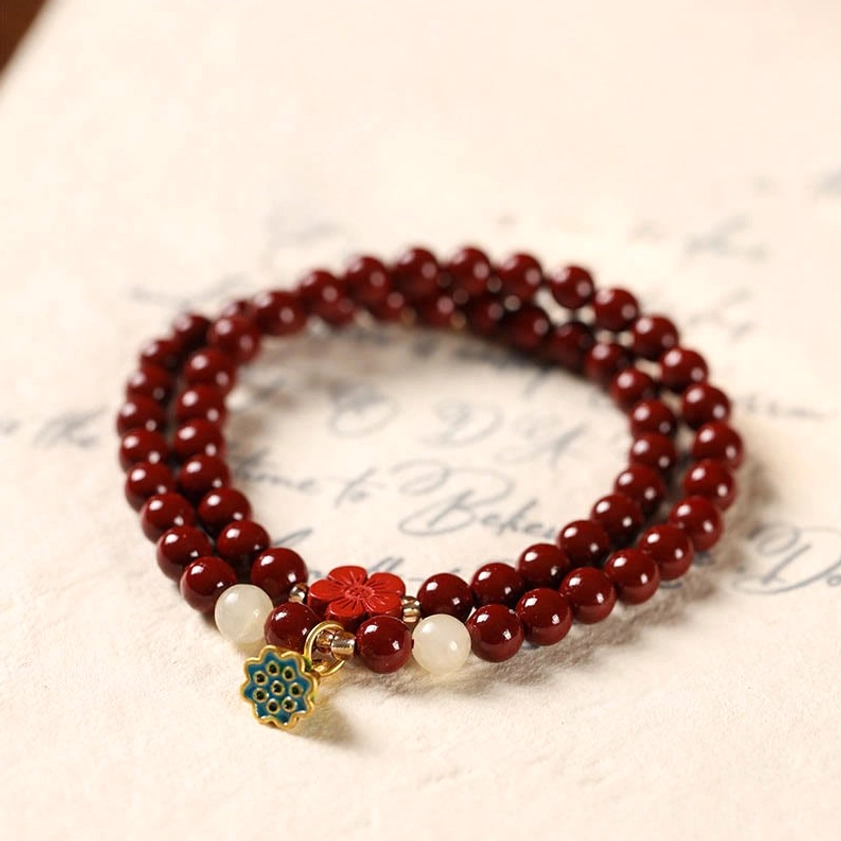 Handmade cinnabar prayer bracelet with mixed accent beads and decorative flower lotus charm on vintage paper