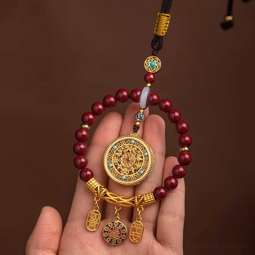Natural cinnabar ruyi car ornament held in palm, featuring ornate gold round pendant and maroon stone beads for spiritual protection
