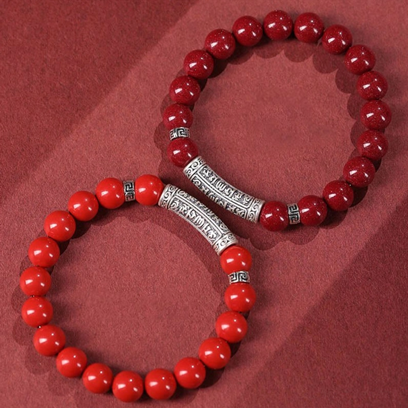 Low angle view of cinnabar and sterling silver mantra bracelet showing engraved details