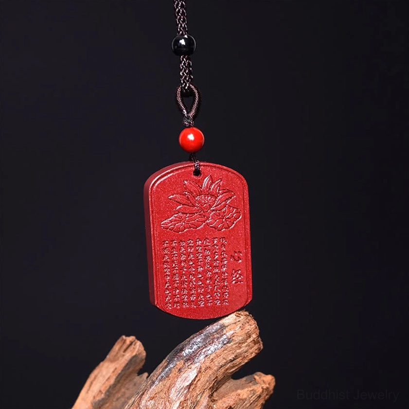 Buddhist heart sutra pendant necklace overhead view on wooden surface with black cord