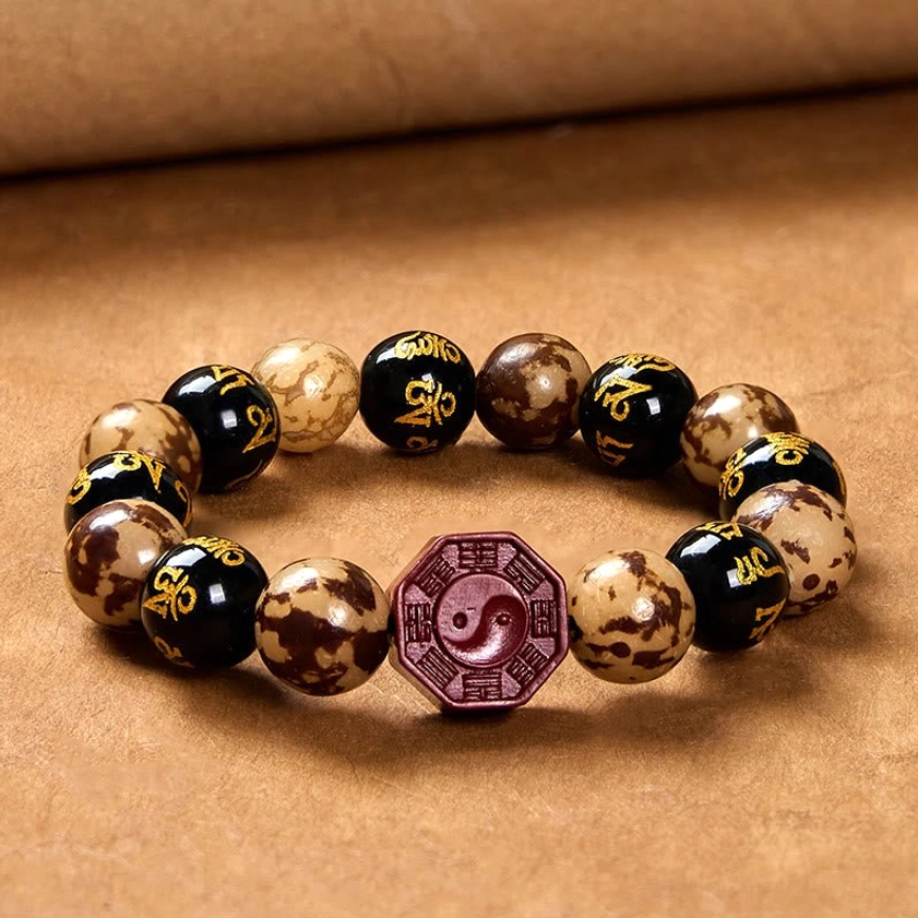 Circular prayer bracelet overhead shot on brown tabletop displaying red cinnabar Bagua focal charm and natural Bodhi seed bead arrangement