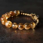 Golden citrine 10mm beads Buddhist bracelet with brass spiral charm and vintage metal spacer on dark background