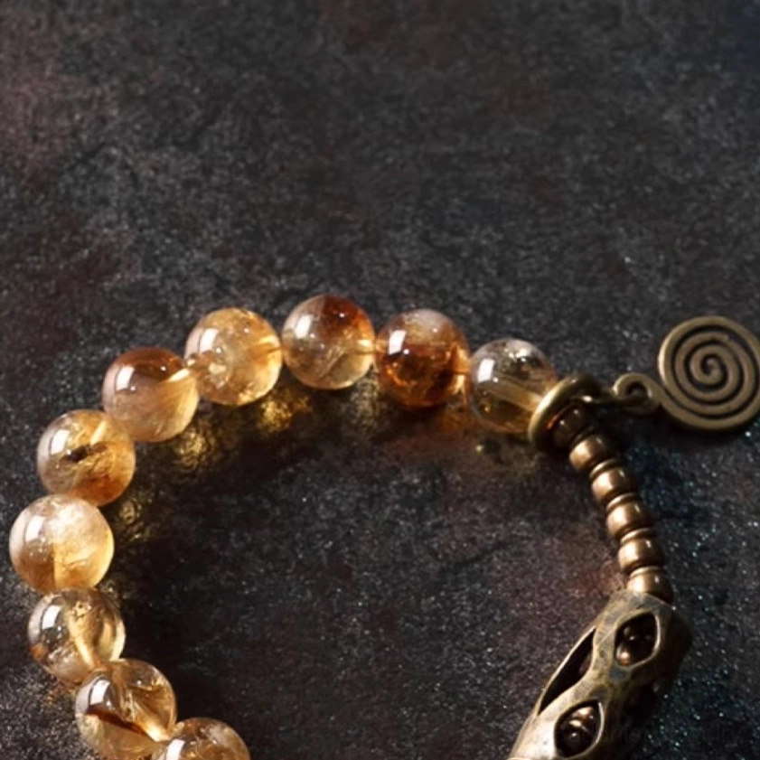 Close-up detail of polished citrine beads and brass metal clasp on handcrafted Buddhist bracelet