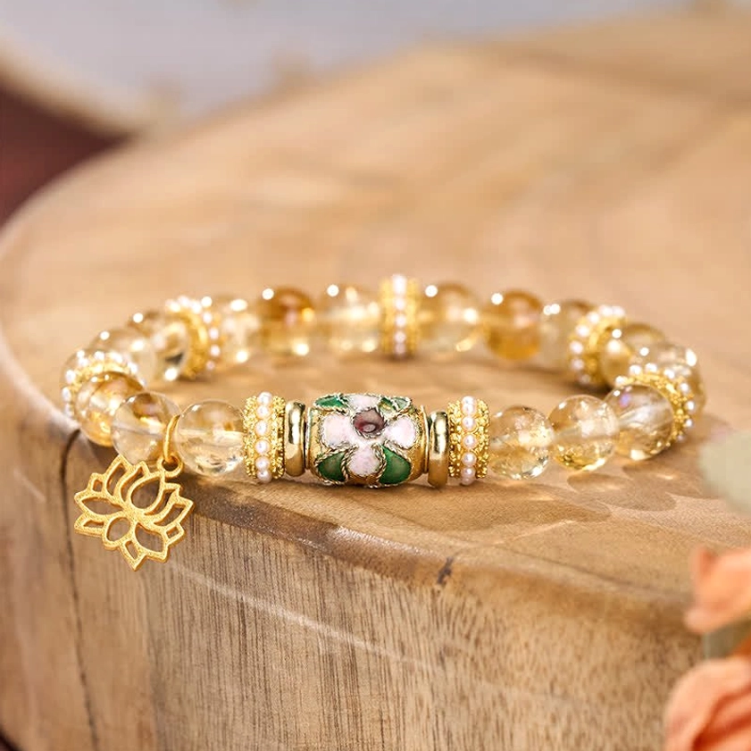 Close-up of citrine lotus bracelet showing translucent yellow beads and intricate enamel lotus centerpiece on wooden display