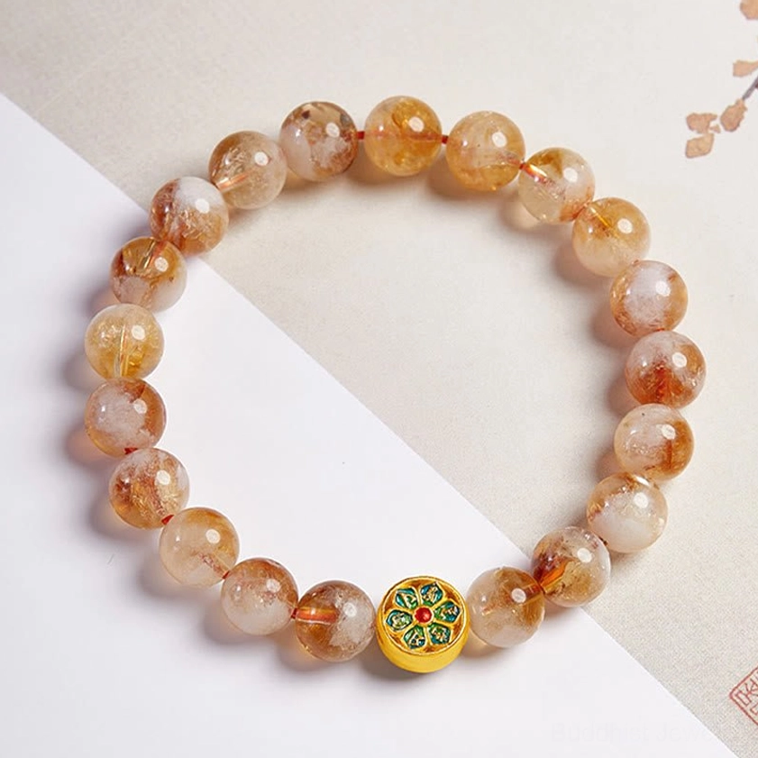 Buddhist citrine bracelet with Om Mani Padme Hum mantra laid flat on textured paper showing bead arrangement