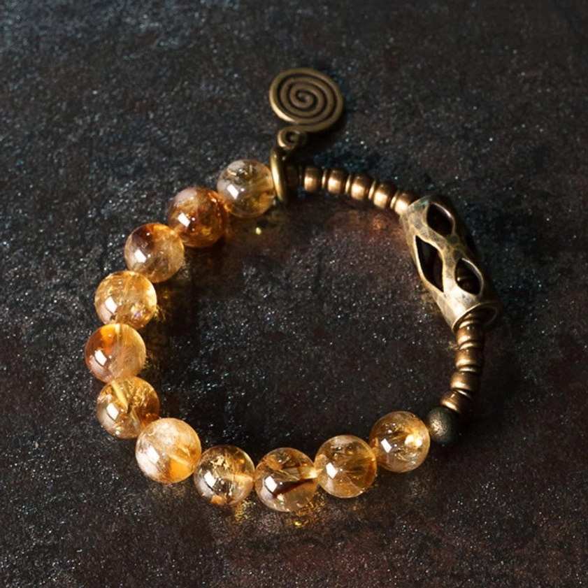 Handcrafted citrine beaded bracelet featuring polished amber beads with brass metal charm overhead view