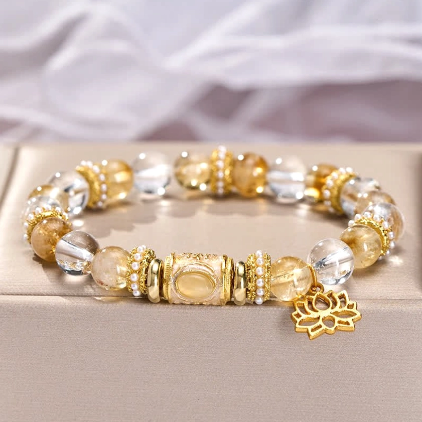 Citrine and clear quartz crystal bracelet with gold lotus charm on gray fabric display