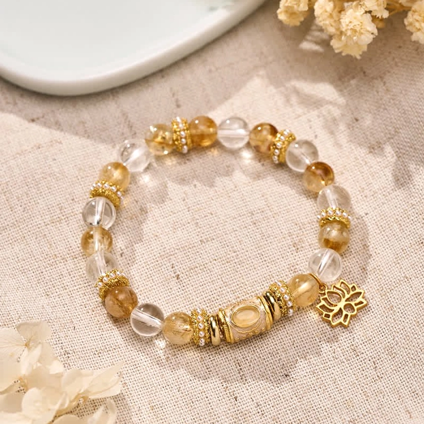 Citrine and clear quartz lotus bracelet flat lay with gold charm on linen background