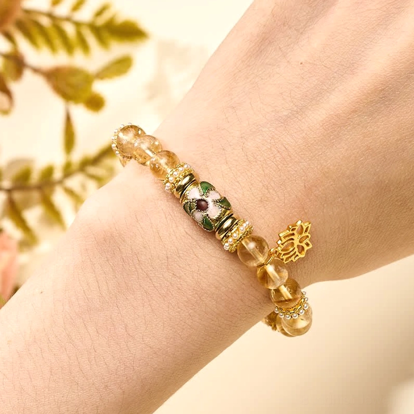 Woman wearing citrine lotus bracelet on wrist with foliage background - styled Buddhist abundance bracelet