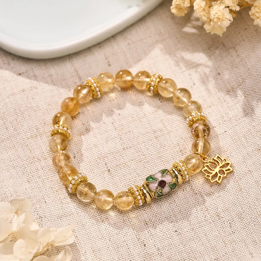 Golden citrine beaded bracelet with cloisonné lotus pendant displayed on linen with dried flowers - handcrafted crystal jewelry