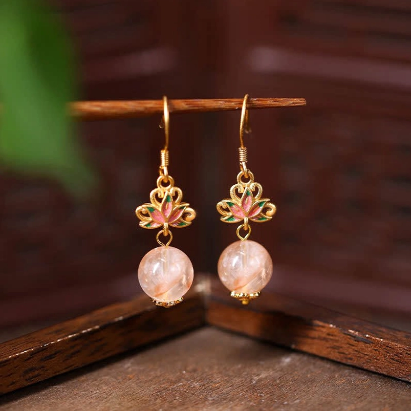 Citrine lotus enamel drop earrings with pink crystal beads and gold ear hooks, front hanging view on dark wood background