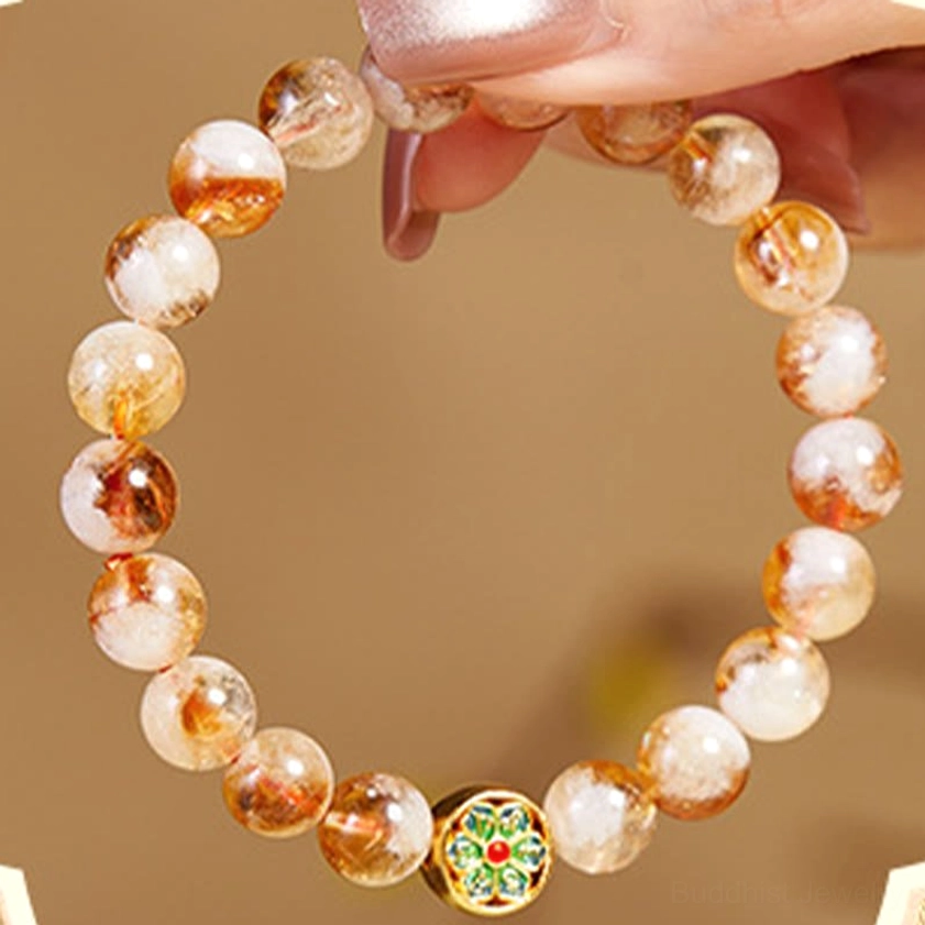 Hands holding citrine beaded bracelet showing loose natural gemstone beads and visible enamel Om mantra charm