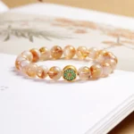 Citrine Om Mani Padme Hum sterling silver bracelet flat lay on Chinese book, showing natural citrine beads with enamel decorated charm