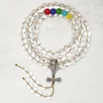 Clear quartz 108 bead mala with silver vajra charm pendant - top-down overhead view showing transparent round beads and colorful chakra accent beads