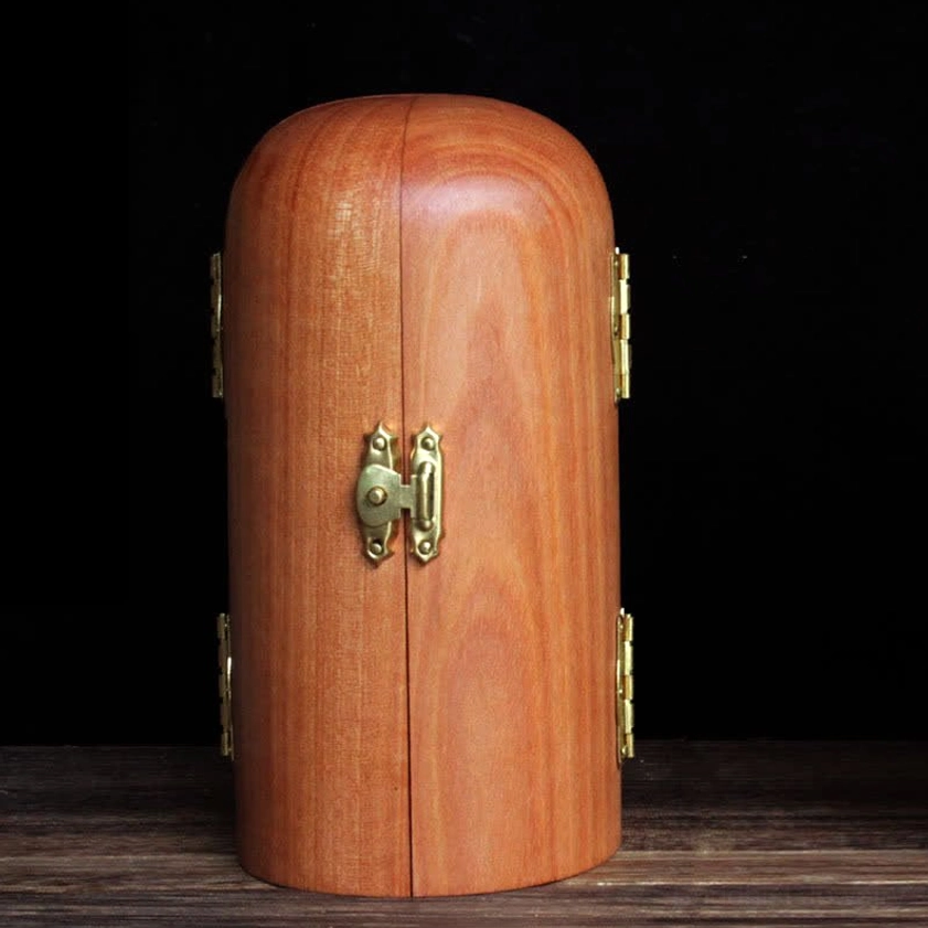 Closed tri-fold Buddhist wooden shrine with arched curved exterior and gilded metal lock on dark wood table