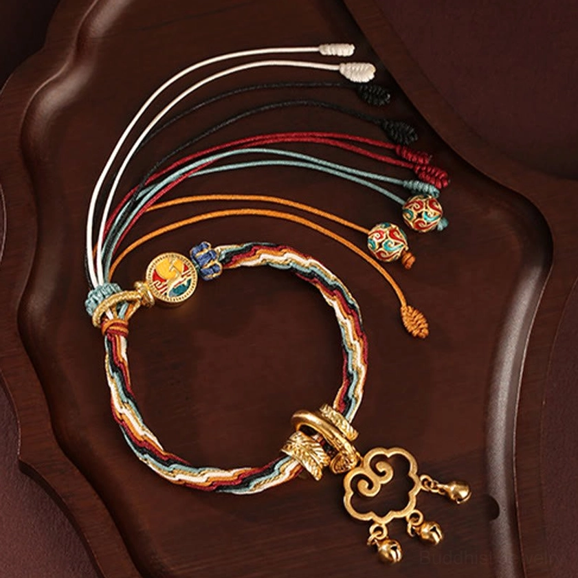 Traditional handmade auspicious cloud lock bracelet with colorful tassel charms and adjustable braided rope on decorative wooden tray