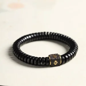 Coconut shell auspicious clouds bracelet with black beads and brass cloud charm, three-quarter view