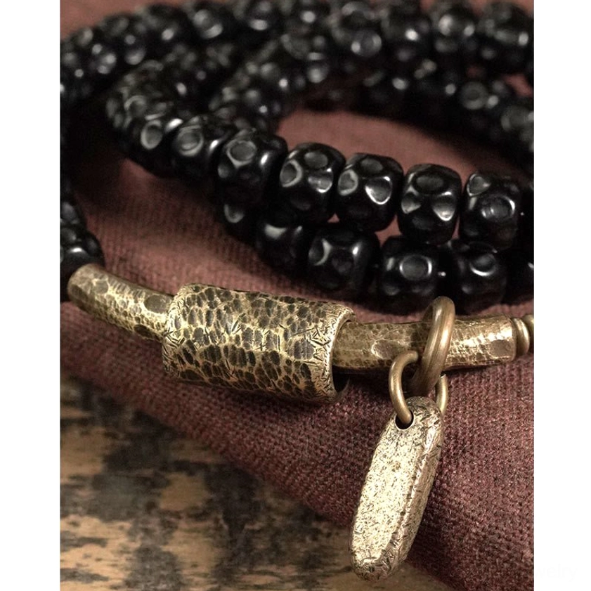Close-up detailed view of coconut shell beads and hammered brass tube accent