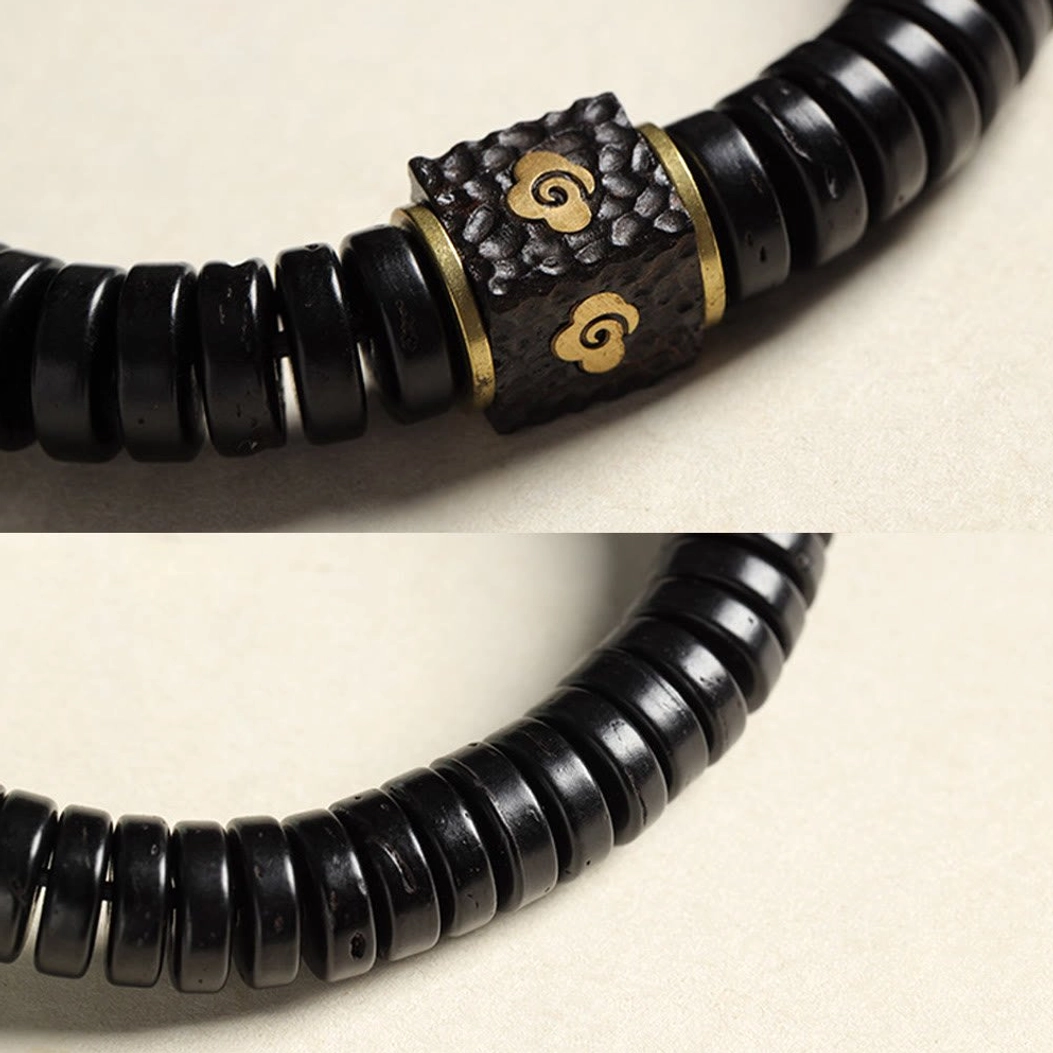 Close-up macro view of brass cloud charm showing hammered metal texture and embossed pattern