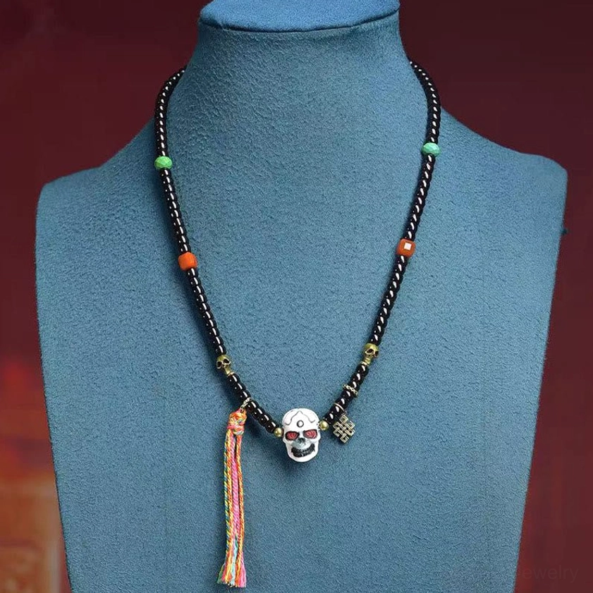 Buddhist skull bracelet worn on wrist showing complete design with colorful tassel
