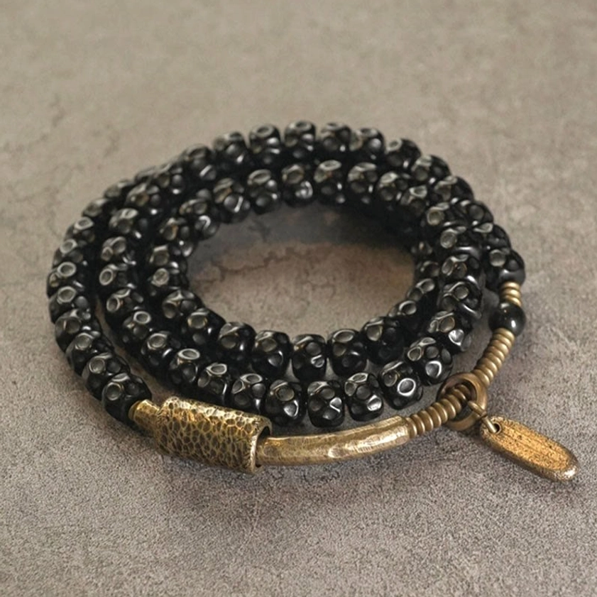 Coconut shell Buddhist bracelet triple wrap design overhead flat lay gray background