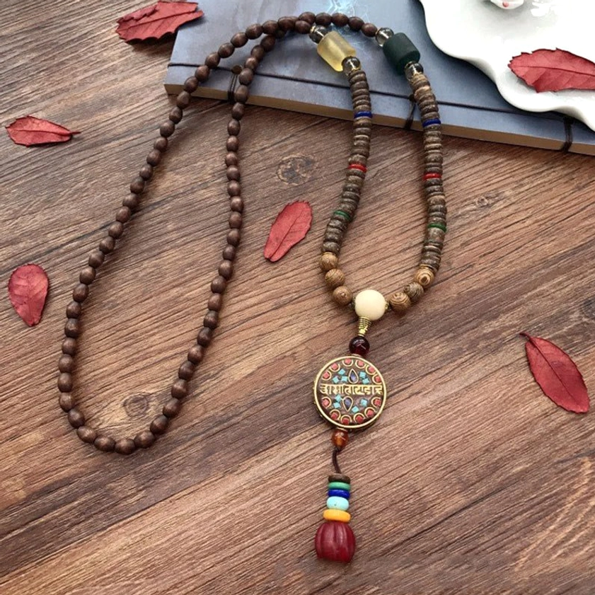 Tibetan-inspired coconut shell necklace with colorful tassel and enamel pendant on wooden desk