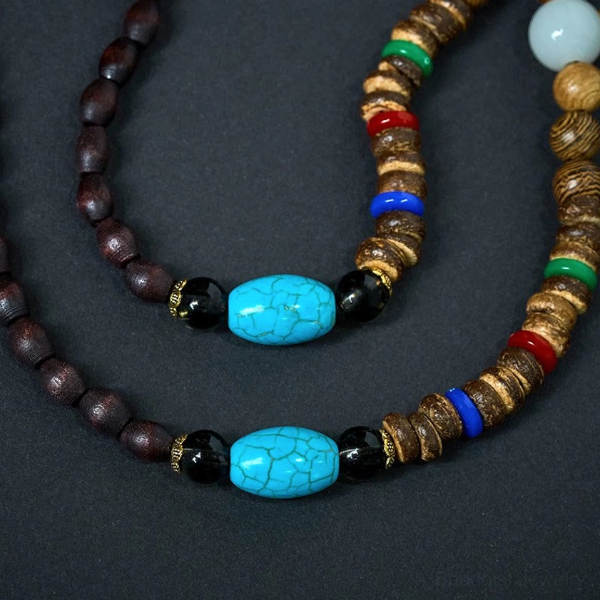 Double-strand Buddhist bead necklace with dark brown beads, turquoise accents and multicolor wooden spacers on dark backdrop