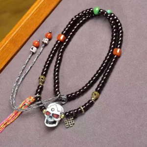 Coconut shell skull prayer bracelet with bone beads and eternal knot charm on wooden surface