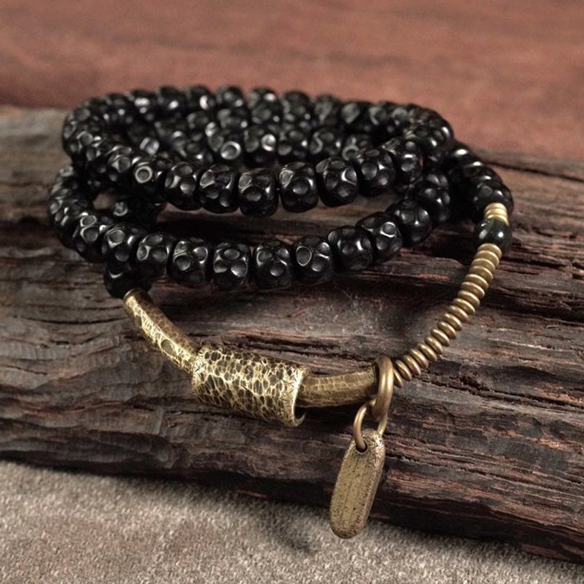 Close-up flat lay of triple wrap coconut shell bracelet with hammered brass tube