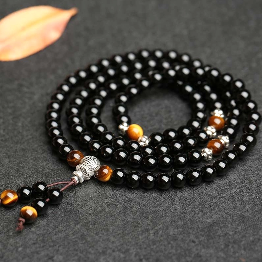 Coiled Buddhist mala beads with tiger eye accents and silver connectors on neutral background