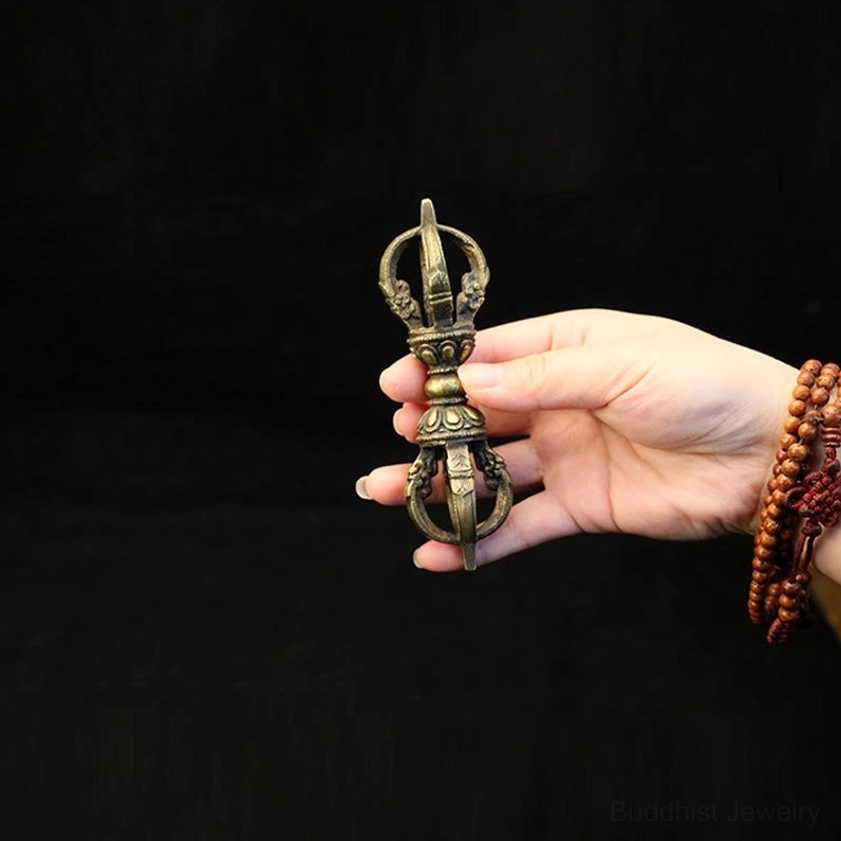 Compact handmade vajra dorje held in hand from side view, demonstrating portable meditation size with antique bronze finish