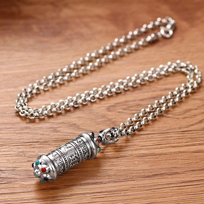 Complete Om Mani Padme Hum necklace with rolo chain and silver-toned hardware laid flat on wooden desktop