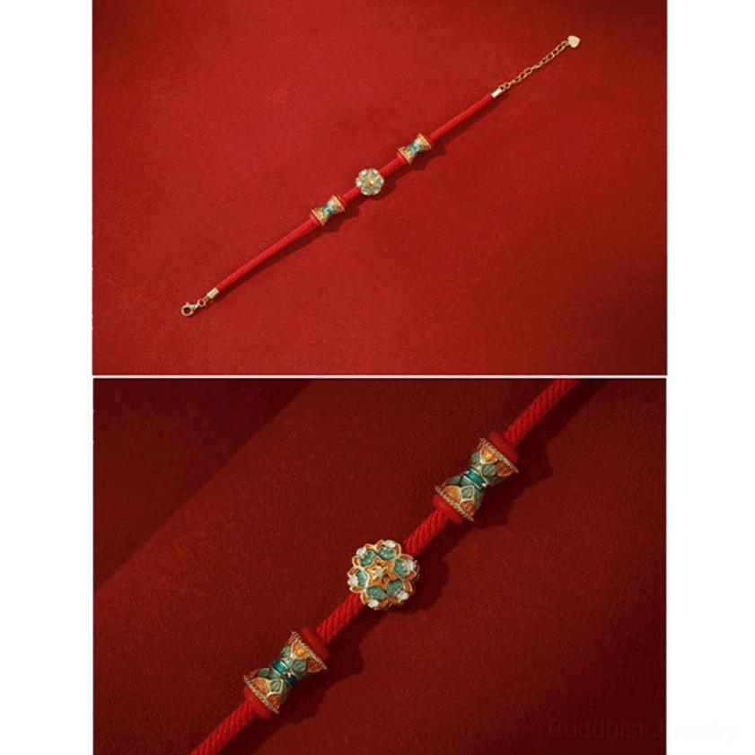 Full length red cord bracelet with sterling silver lotus and barrel charms laid flat