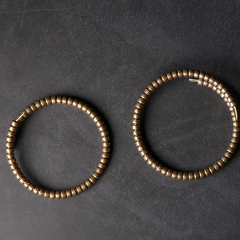 Matching copper balance cuff bracelets, flat lay showing uniform disk bead pattern and open cuff structure