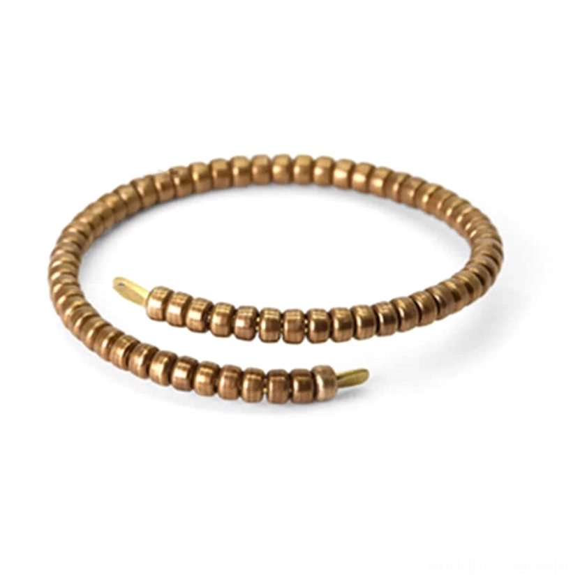 Macro close-up of copper balance cuff bracelet terminal and disk beads, matte bronze metallic texture