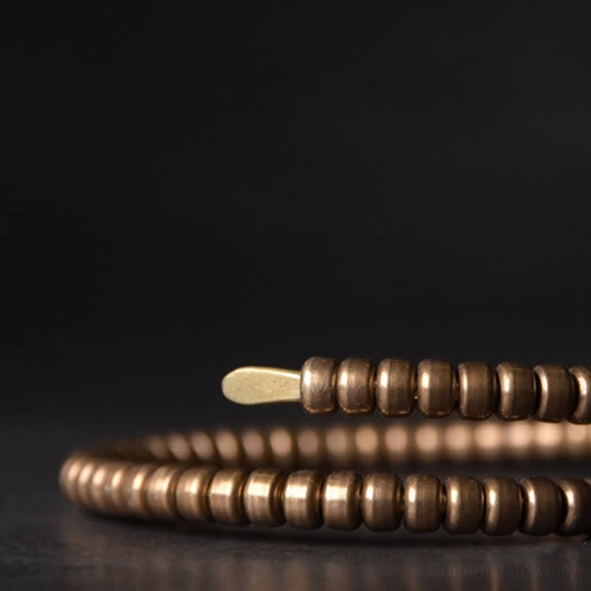 Close-up view of stacked copper balance cuff bracelets showing disk bead details and antiqued finish
