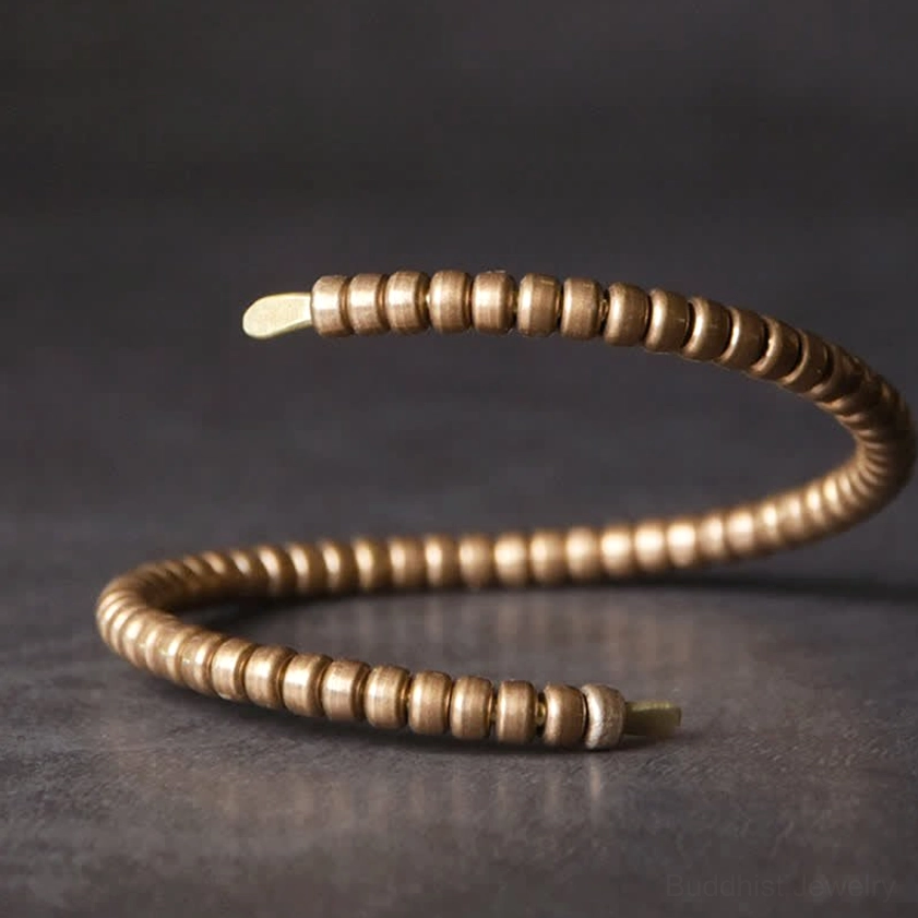 Single open copper balance cuff bracelet side view, showing flat metal end caps and disk bead details