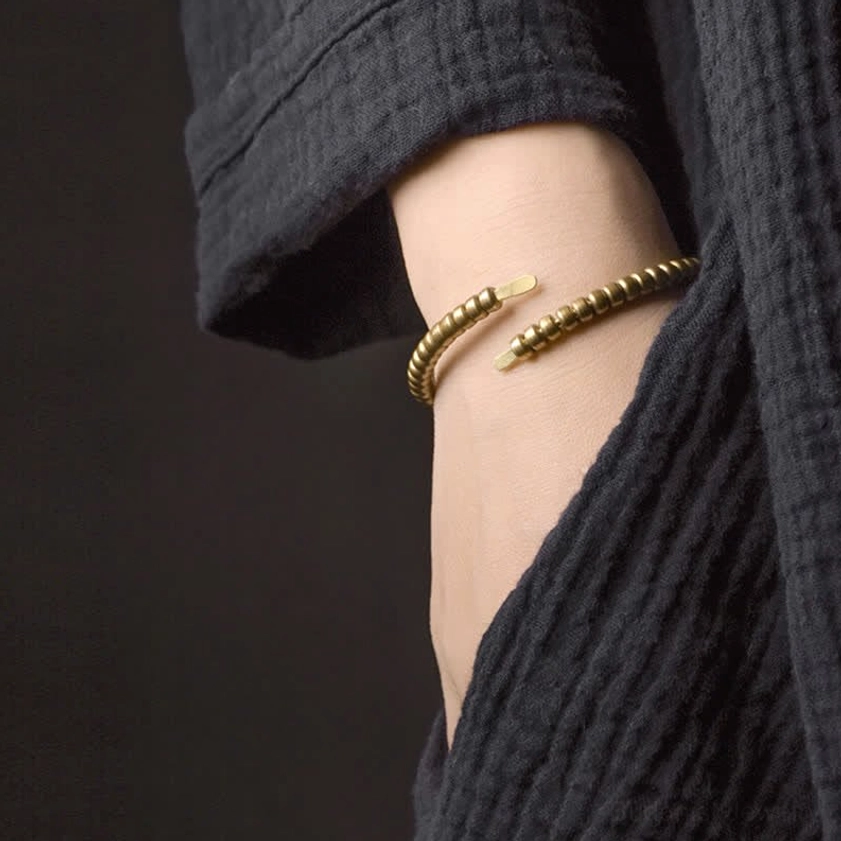 Dual stacked copper balance cuff bracelets worn on wrist, antique bronze finish with aged patina detail