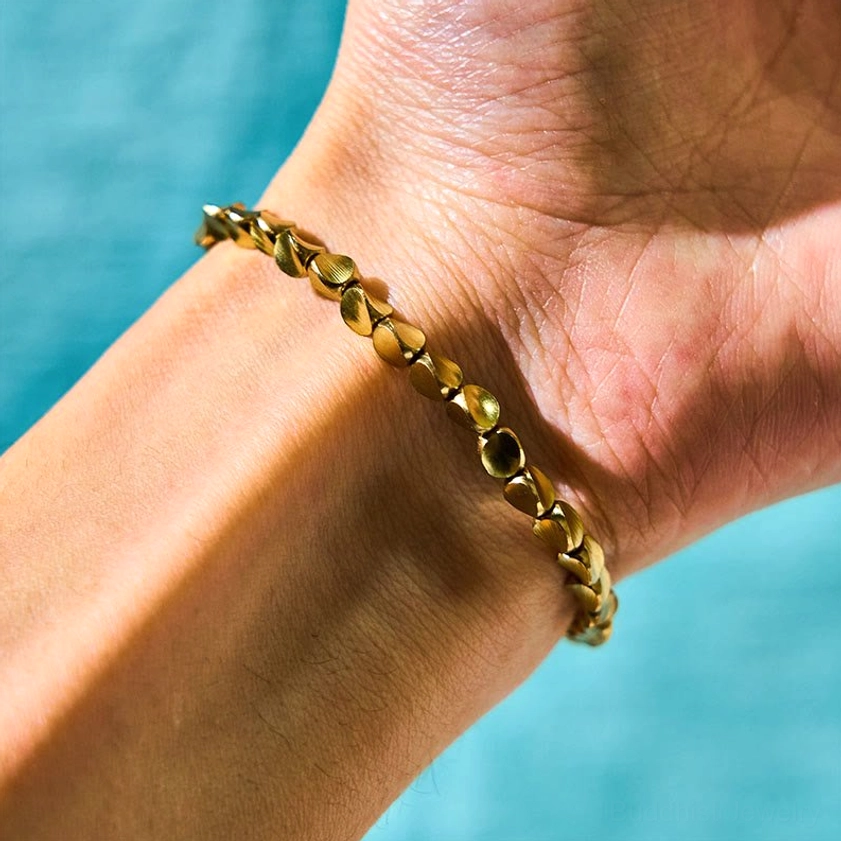 Shiny copper bead bracelet worn on wrist with light blue background, showing polished metallic finish and comfortable fit for spiritual practice