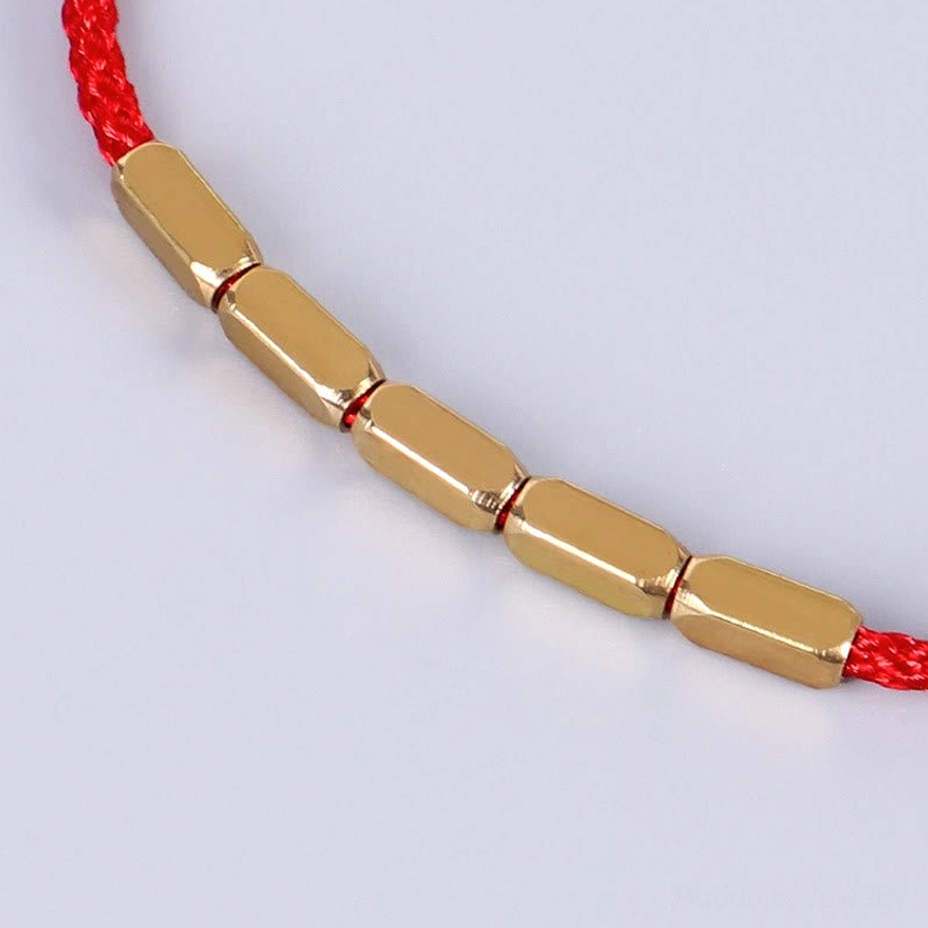 Side close-up view of copper bead Buddhist protection bracelet showing polished metal beads and braided cord texture