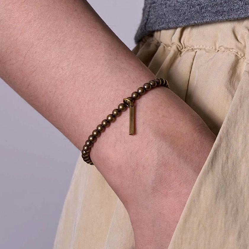 Copper brass beaded bracelet in dark bronze tone worn on female wrist with side view perspective against casual outfit