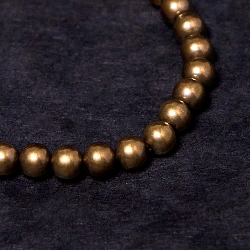 Low-angle close-up of smooth round copper metal beads with warm antique bronze finish