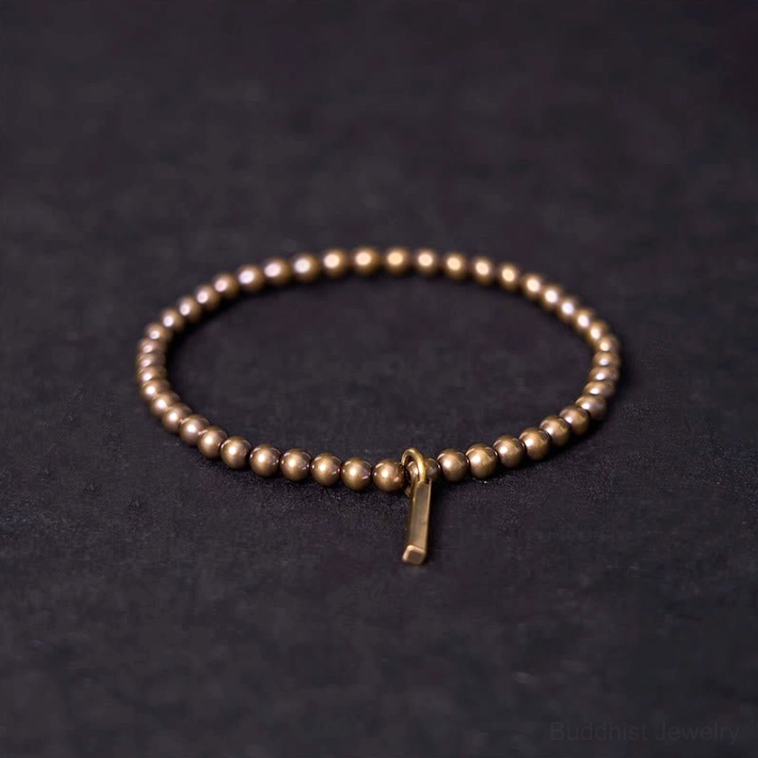 Close-up angled view of antique bronze copper beads and metal pendant charm on elastic bracelet string