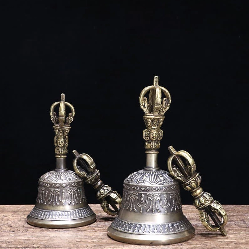 Handcrafted copper meditation bell and five-pronged vajra dorje set on wooden table with black backdrop, showing dual-tone bronze and silver-gray finish
