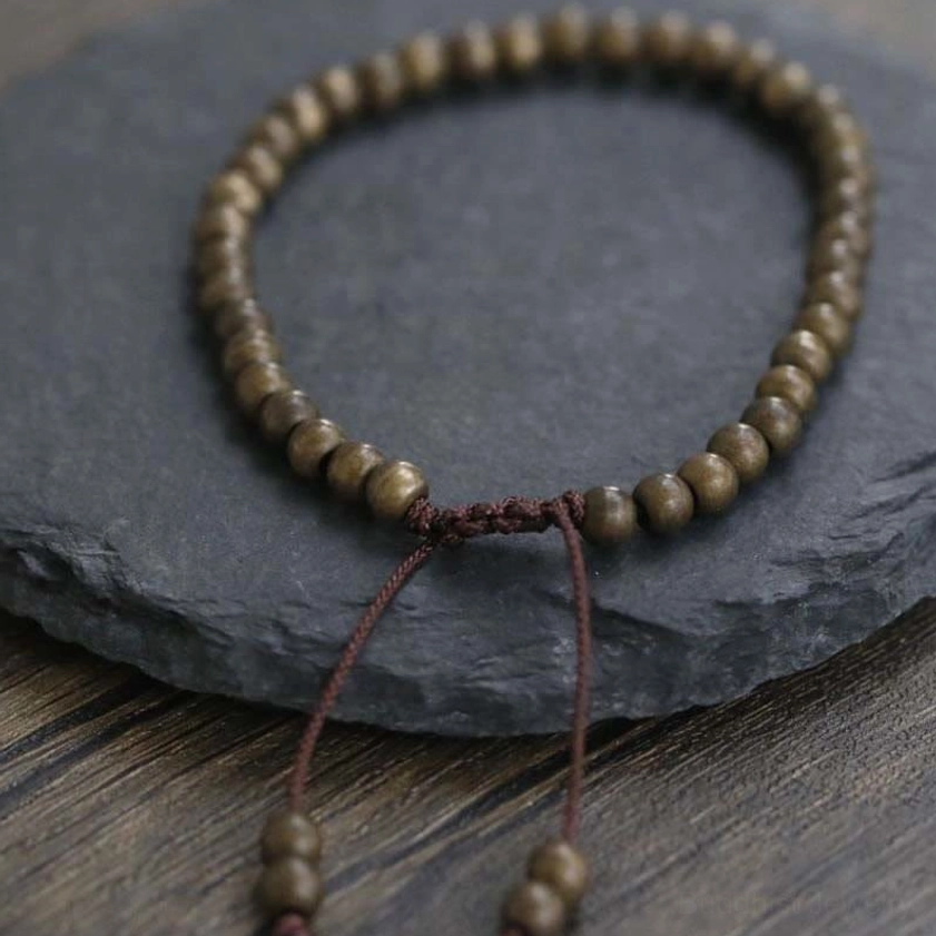 Copper bead bracelet close-up with braided knot and long adjustable drawstrings for wealth attraction