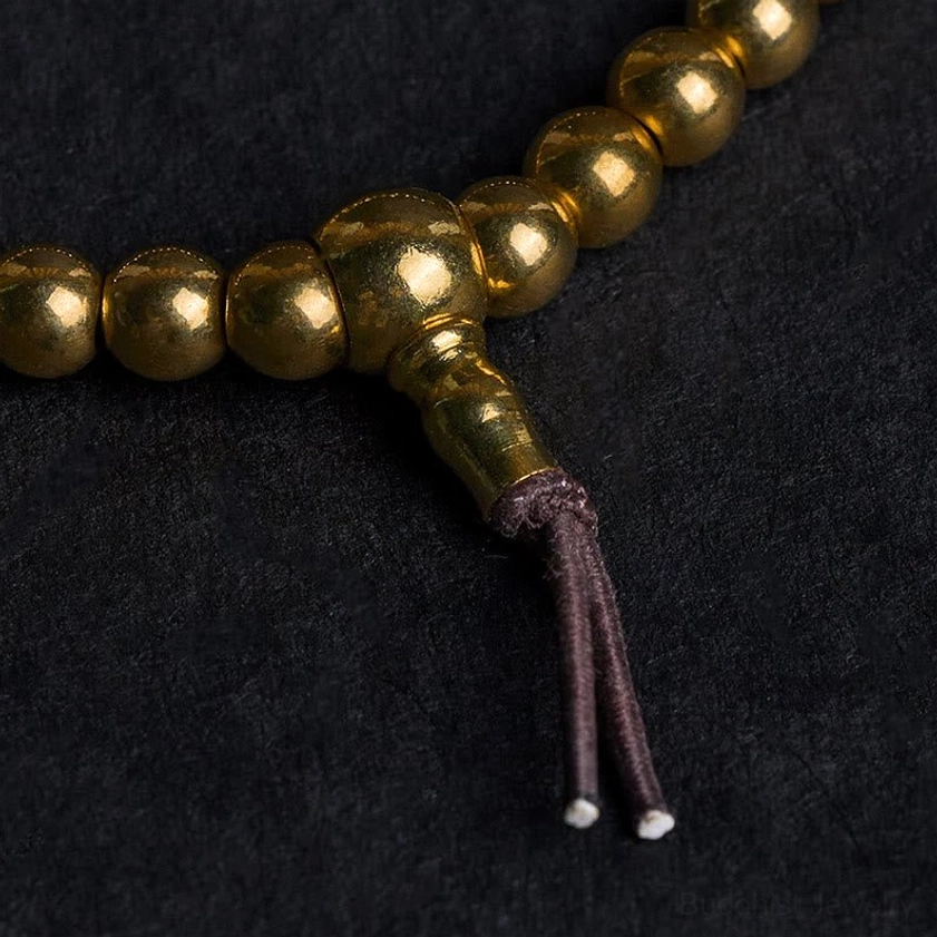 Close-up macro shot of polished brass guru bead joint and leather tassel connector